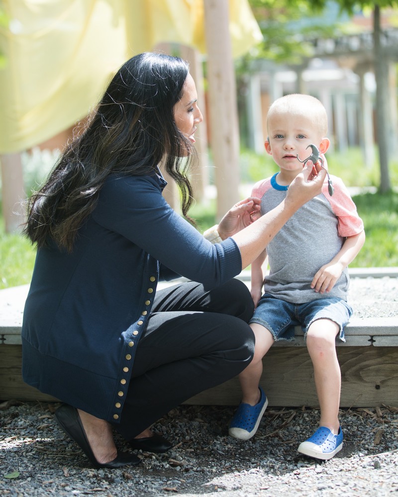 A female student helping a child with cochlear implants during class.