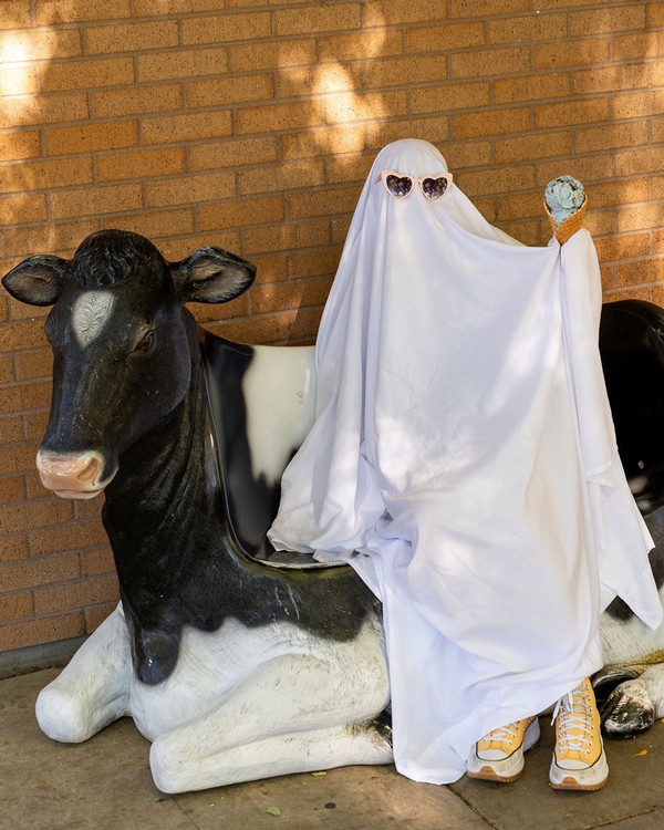 A person in a ghost costume enjoys an ice cream cone