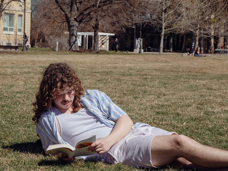USU student reading a book while enjoying the spring weather on the quad