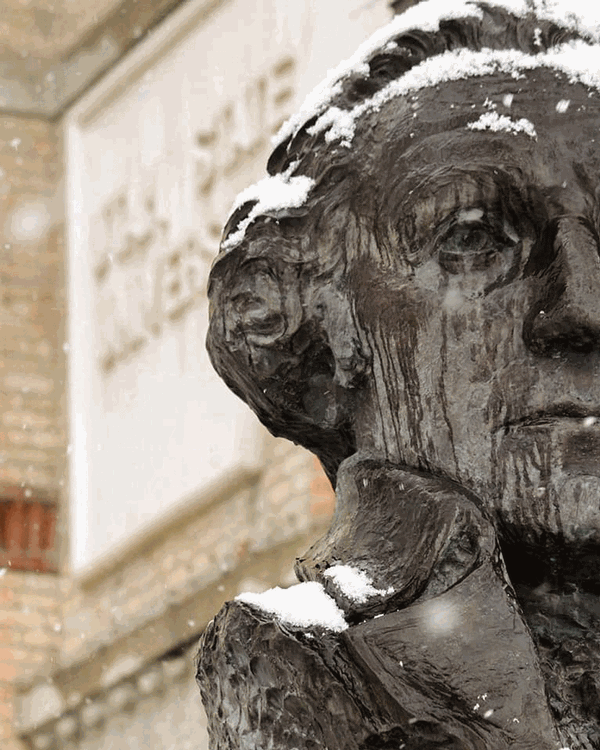 A photo of a snow covered George Washington bust just outside of Old Main at Utah State University.