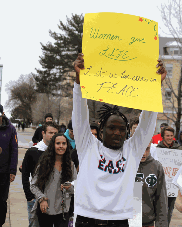 Student holding a sign which reads,