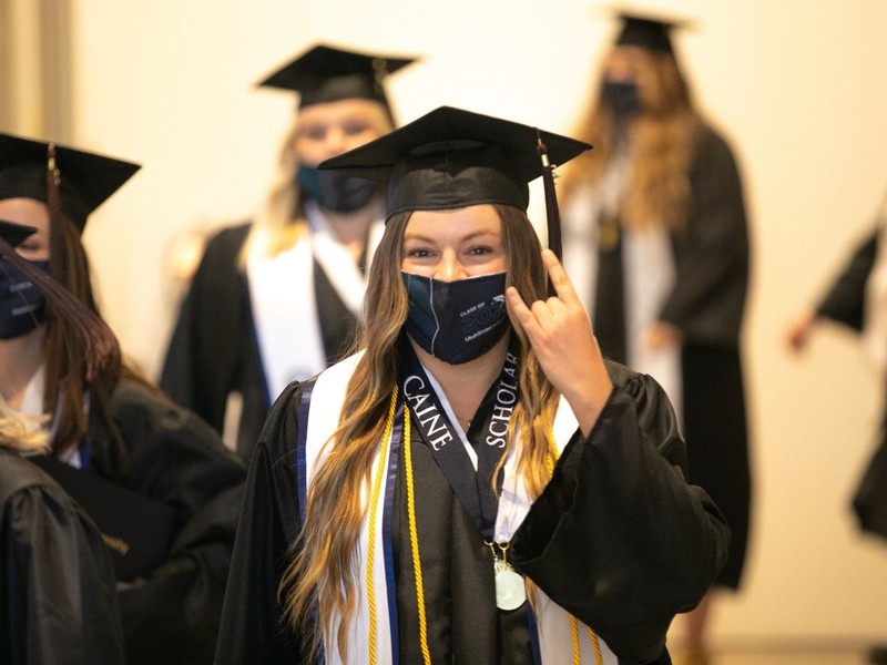 A USU graduate holds up the Aggie 