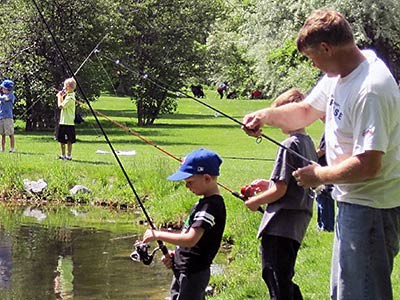 a father and two boys fishing at a pond at free fishing day
