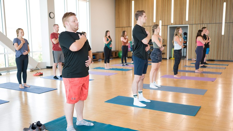 Students stand on yoga mats doing a yoga pose