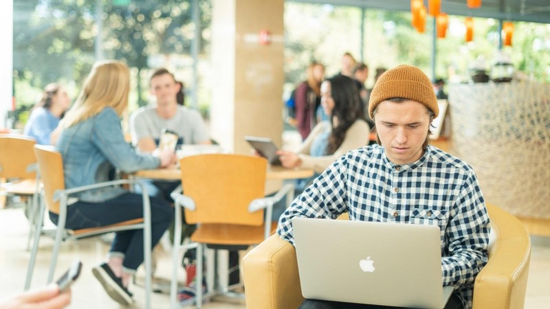 A man uses a laptop in a cafe on the USU campus.