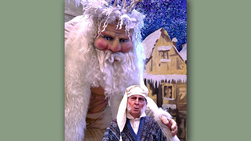 A larger-than-life puppet posing with an actor playing Ebenezer Scrooge.