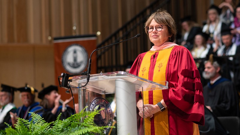 Rachel Nardo stands at the lectern at the Caine College of the Arts convocation ceremony.