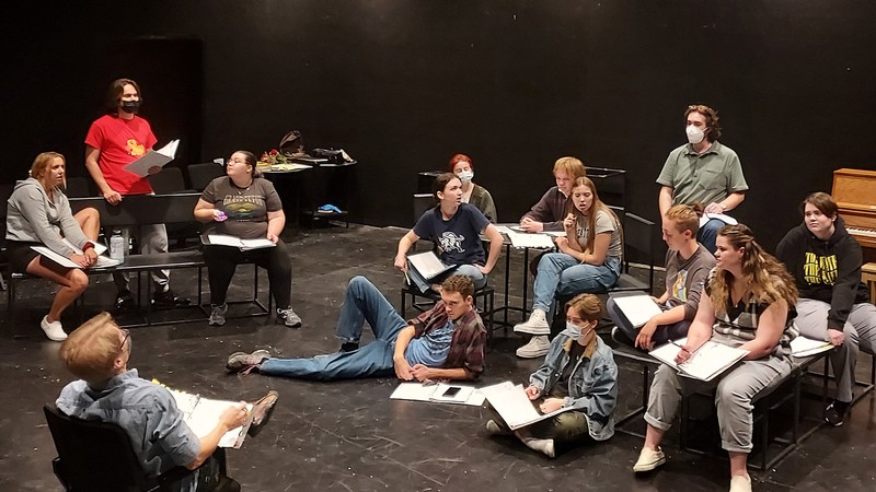 Students rehearsing a play in a black room.
