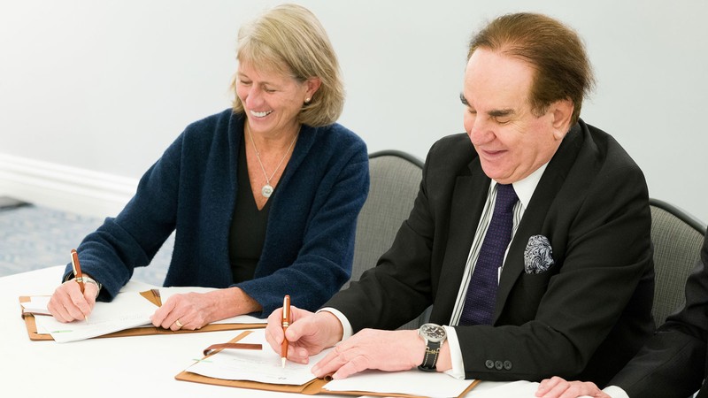 Noelle Cockett and Mehdi Heravi signing documents.