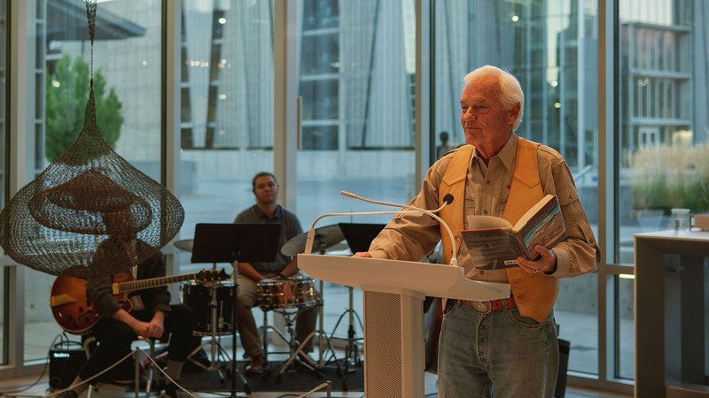 David Lee reading from a book of poetry at an open mic event.