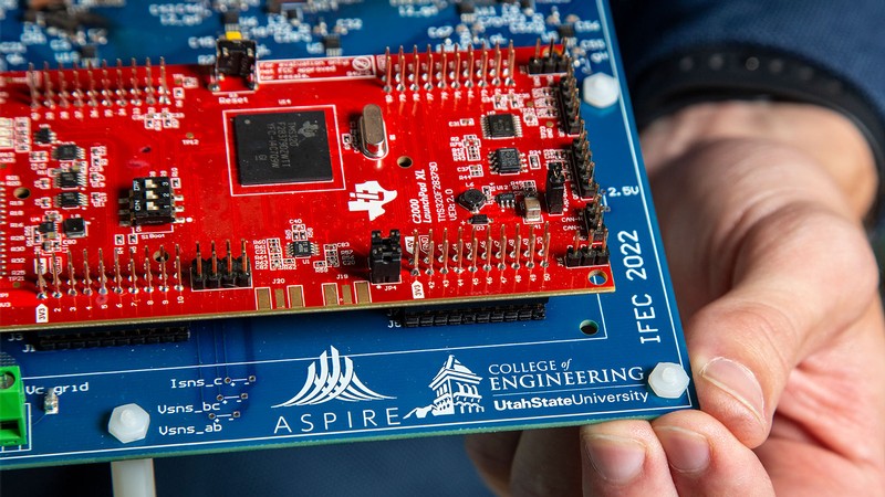 An electrical device's printed circuit board shows the USU ASPIRE and College of Engineering logos.