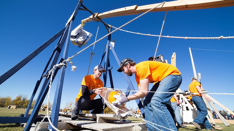 Students loading a pumpkin into the sling of a trebuchet.