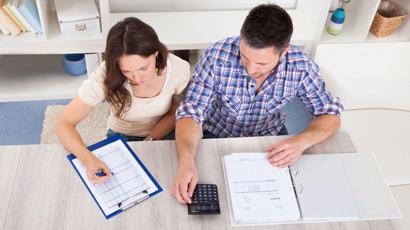 Two people sit side-by-side as they calculate finances.