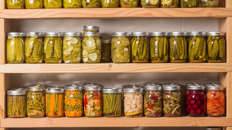 A shelf holds jars of pickled vegetables.