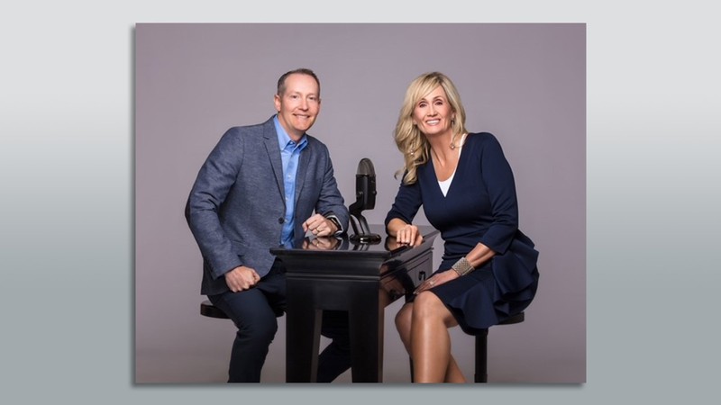 Dave Schramm and Liz Hale posing next to a podcast microphone.
