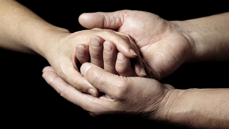 Two people's hands holding each other.