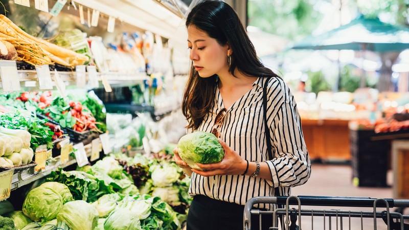 A person examines lettuce at the supermarket.