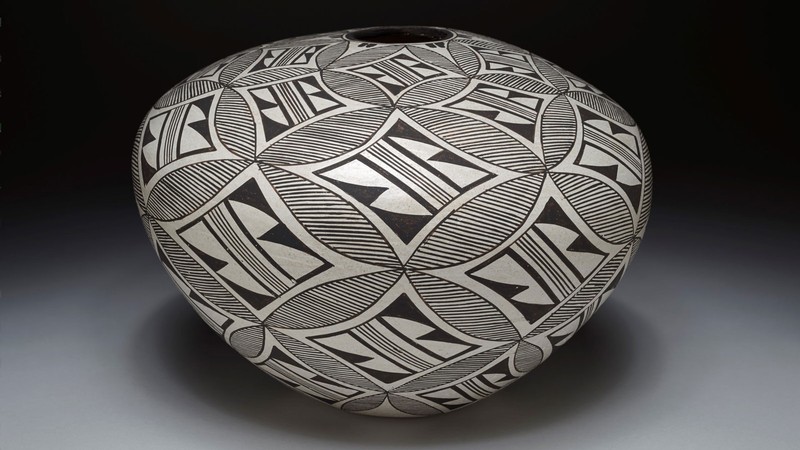 A round piece of pottery shows an intricate black-and-white pattern.