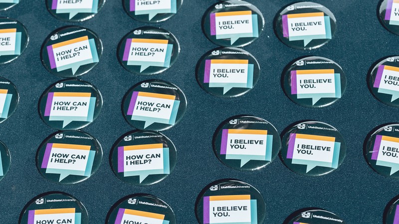 Pinback buttons arranged on a table state "I believe you" and "how can I help?"