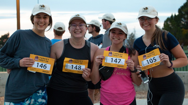 Runners holding up their race entry numbers for a photo.