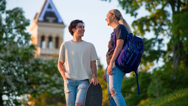 Two people talk to each other in front of Old Main on the USU Logan campus.