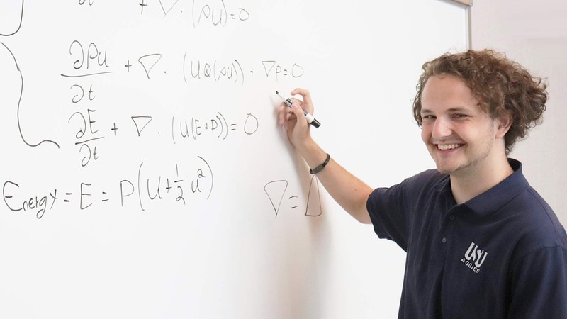 Owen Graham writing equations on a whiteboard.