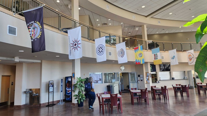 Several Native American flags hanging in a building lobby.