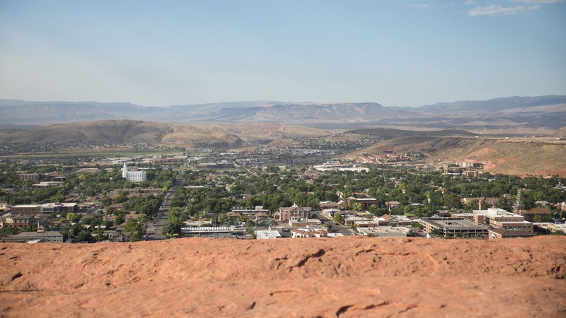 The city of St. George is seen from a rocky hillside.