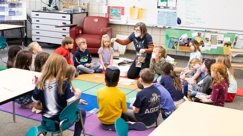 First graders sit in a circle and listen to their teacher, Shannon Rhodes.