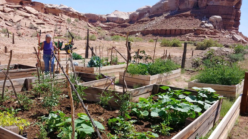 A woman works on a garden among redrock formations in Southern Utah.