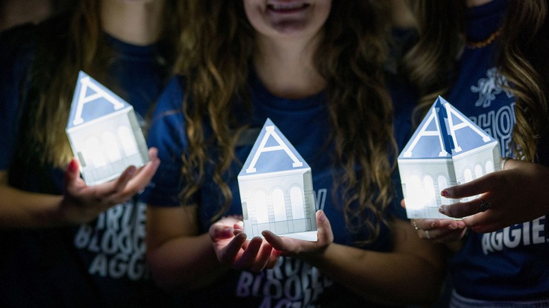Students hold lanterns shaped like Old Main's tower.