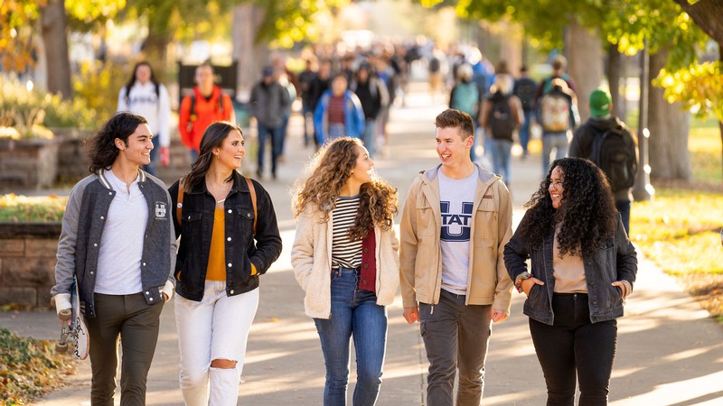 Students walk along a sidewalk.
