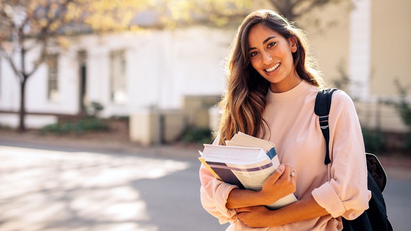 A woman holds textbooks.