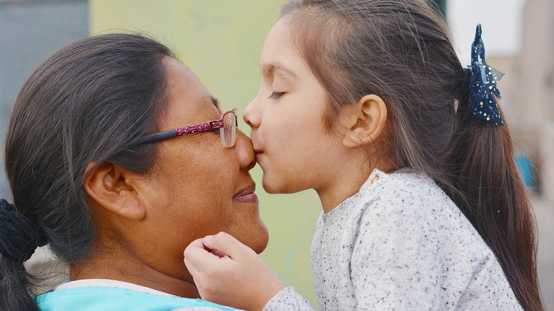 A child kisses an adult on the nose.