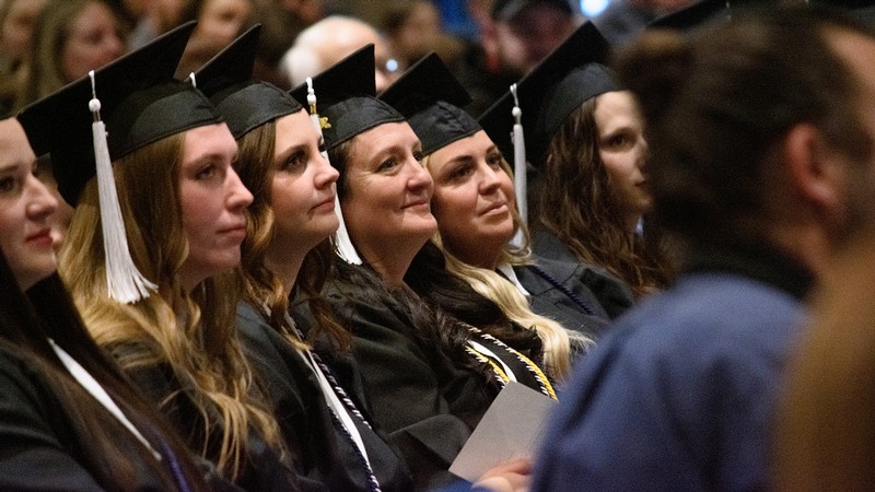 Graduates sit in chairs listening