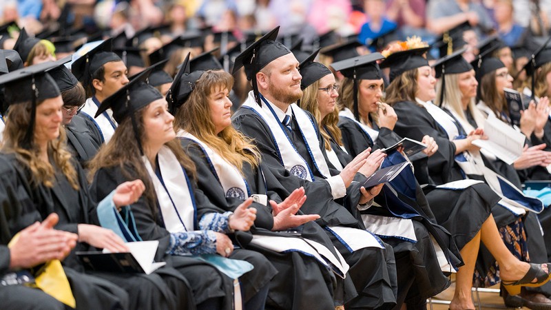 Graduates sit in chairs listening