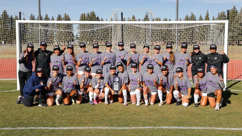 The USU Women's Soccer team posing for a photo in a goal.