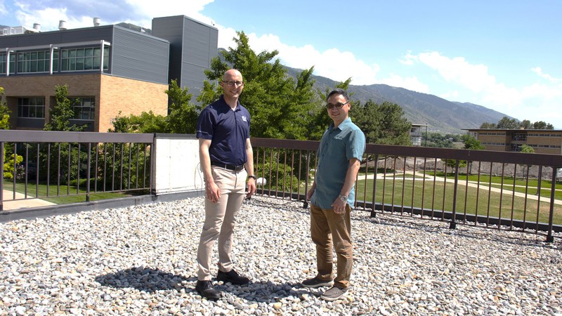 Two men stand on a rooftop.