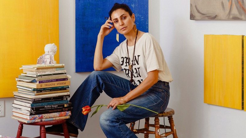 An artist sitting next to a stack of books.