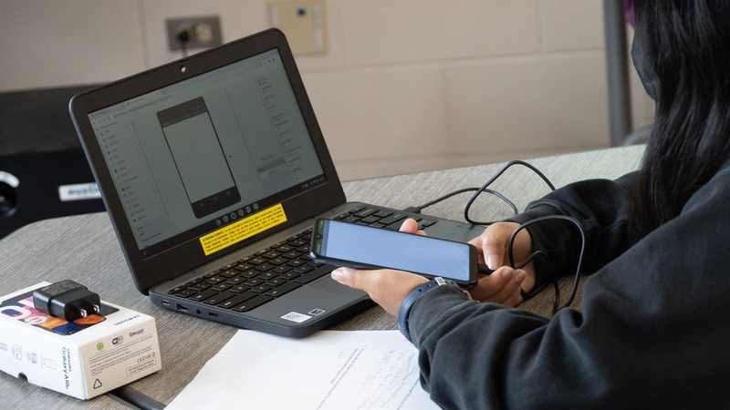 Person plugs a cell phone into a laptop