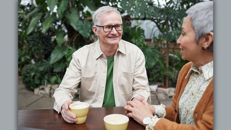 Two older people holding hands and talking.