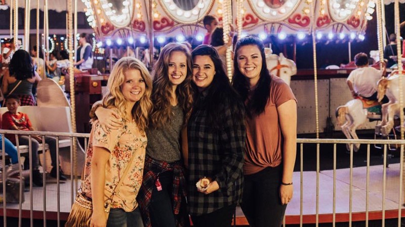 Women standing in front of a carousel.
