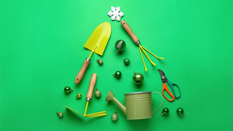 Gardening tools and ornaments laid out in the shape of a Christmas tree.