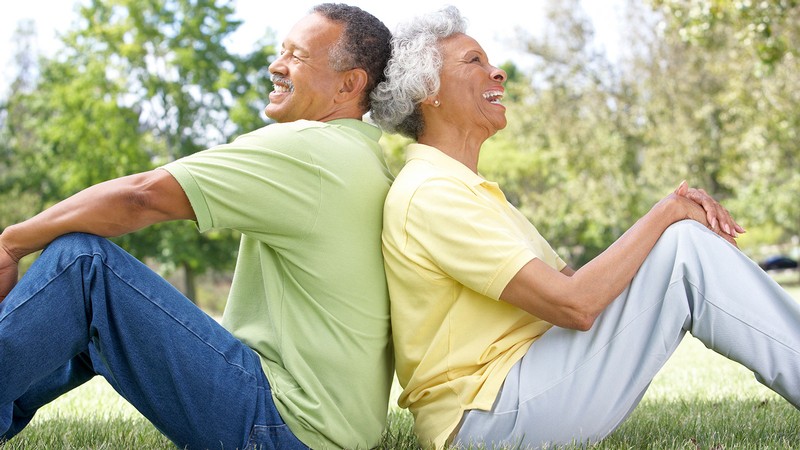 A married couple sitting on the grass together.
