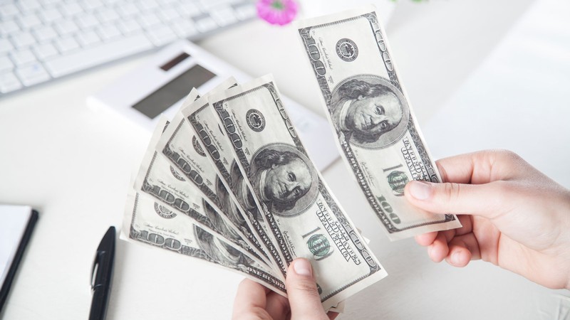 A person holding 100-dollar bills.