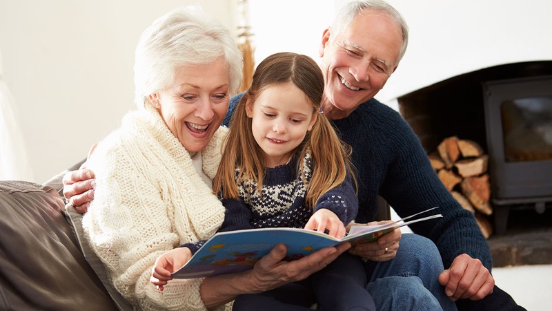 A child reading a book with grandparents.