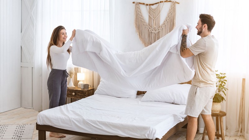 Two people making a bed.