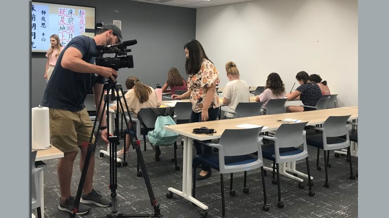 A person setting up a camera in a classrooom.