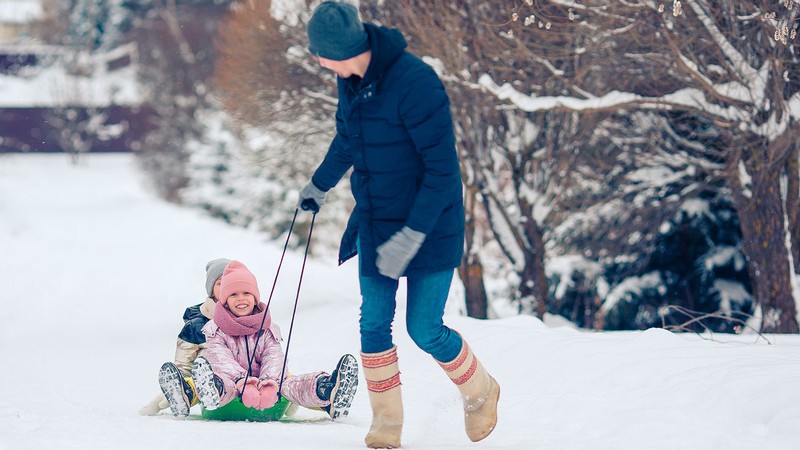 A person pulling children on a sled.