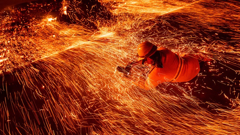 A person taking a photograph amid sparks from a wildfire.